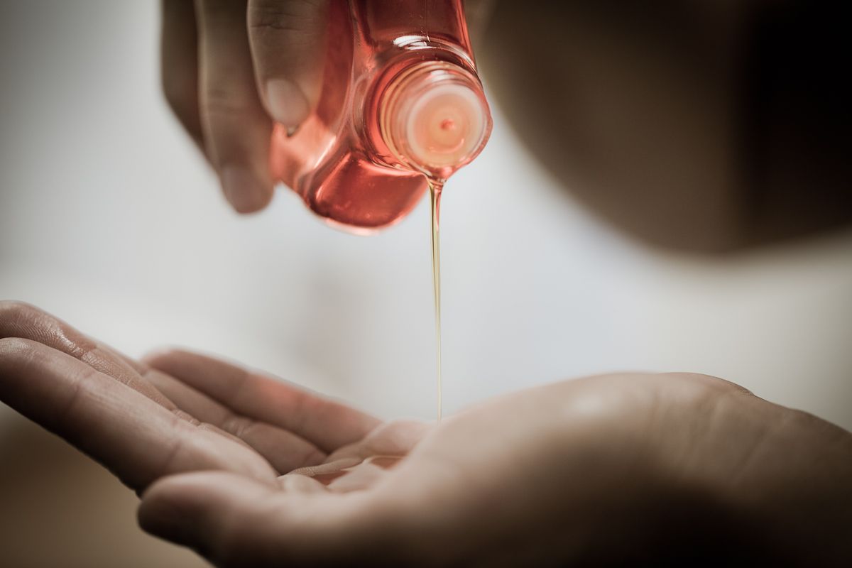 Care oil flowing from a small bottle into an open palm